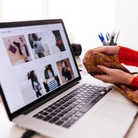 close-up of fashion designer in studio with laptop examining fabric - fashion stock pictures, royalty-free photos & images