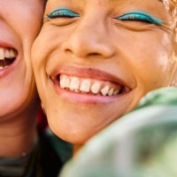 close-up of two gen z adults smiling and laughing outdoors. urban environment. friendship and well-being. - fashion stock pictures, royalty-free photos & images