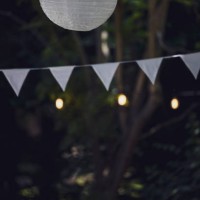 close-up of white flag garland and paper lantern against trees. garden party, summer festival, birthday party, baptism or wedding. - garden decoration stockfoto's en -beelden