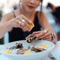 close-up of woman's hand squeezing lemon juice on fresh oysters - food stock pictures, royalty-free photos & images