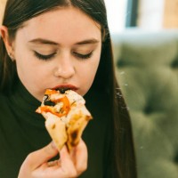 close-up portrait of a teenager girl eating pizza - junk food stock pictures, royalty-free photos & images