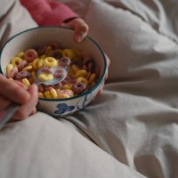 close-up view of an unrecognisable caucasian girl, eating a bowl of cereal for breakfast in bed after waking up. - junk food stock pictures, royalty-free photos & images