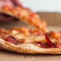 close-up view of pizza with one person's hand taking a slice - junk food stock pictures, royalty-free photos & images