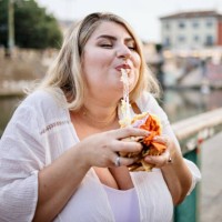 close up of a woman eating and enjoying fast food outside - junk food stock pictures, royalty-free photos & images