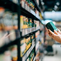 close up of a woman grocery shopping in supermarket. holding a tin can and reading the nutrition label at the back - junk food stock pictures, royalty-free photos & images