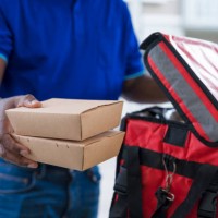 close up of an unrecognizable courier man making food delivery, carrying takeaway paper boxes to your doorstep. - junk food stock pictures, royalty-free photos & images