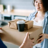close up of beautiful and cheerful young asian woman receiving home delivery takeaway food order from a delivery man at home. eating at home concept - junk food stock pictures, royalty-free photos & images
