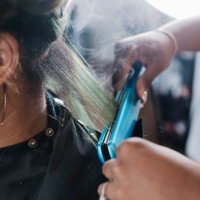 close up of black hairdresser straightening client's hair - hairstyle stock pictures, royalty-free photos & images