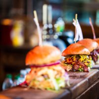 close up of fresh flame grilled burgers displayed in a row at food market - junk food stock pictures, royalty-free photos & images
