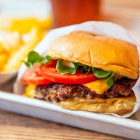 close up of juicy cheeseburger with fresh tomatoes - junk food stock pictures, royalty-free photos & images