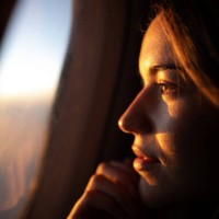 close up of pensive woman looking at sunset through airplane window. - travel stock pictures, royalty-free photos & images