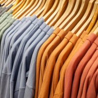close up of stack of t-shirts on hangers and racks in department store in london, uk. plain standard style shirts in original stone wash and earthy colours and patterns - fashion stock pictures, royalty-free photos & images