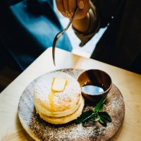 close up of woman eating fluffy pancake with butter and syrup on dinning table - junk food stockfoto's en -beelden