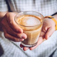 close up of woman hand holding a cup of dirty latte before drink it. - coffee stock pictures, royalty-free photos & images