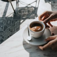 close up of woman's hand holding a cup of coffee, drinking coffee in outdoor cafe against beautiful sunlight, having a relaxing moment. enjoying life's simple pleasures - coffee stock pictures, royalty-free photos & images