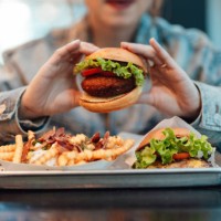 close up of young asian woman eating burger and fries in restaurant - junk food stock pictures, royalty-free photos & images