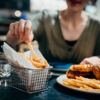close up of young asian woman enjoying freshly served delicious burger with french fries in a restaurant. eating out lifestyle - junk food stock pictures, royalty-free photos & images