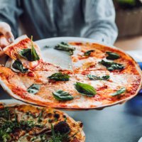 close up of young asian woman getting a slice of freshly made pizza. enjoying her meal in an outdoor restaurant. italian cuisine and culture. eating out lifestyle - junk food stock pictures, royalty-free photos & images