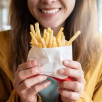 close up of young asian woman holding a french fries before eating. - junk food stock pictures, royalty-free photos & images