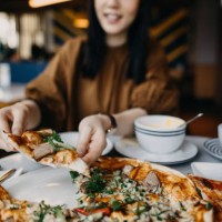 close up of young woman enjoying meal and eating freshly made pizza in a restaurant - junk food stock pictures, royalty-free photos & images