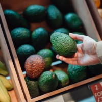 close up shot of woman’s hand holding avocado in grocery store - food stock pictures, royalty-free photos & images
