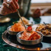 closeup of woman eating kimchi with chopsticks in korean restaurant - food stock pictures, royalty-free photos & images