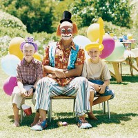 clown sitting on a chair with two young boys in a garden - garden decoration stockfoto's en -beelden