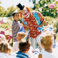 clown standing with boy and entertaining children at a birthday party - garden decoration stockfoto's en -beelden