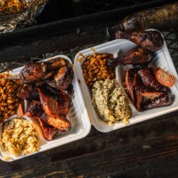 compostabale takeout container full of smoked bbq beans, sausage, chicken thighs & drumsticks, and dirty rice from a food truck or traveling smoker catering company - junk food stock pictures, royalty-free photos & images