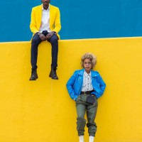 confidence portrait of two young black friends standing against a yellow wall. young trendy african man and latin american woman looking at camera outdoors. friendship and diversity concept. - fashion stock pictures, royalty-