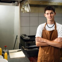 confident caucasian teenage boy working at a fast food restaurant kitchen - junk food stock pictures, royalty-free photos & images