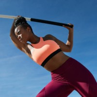 confident sportswoman holding pole vault against blue sky - fashion stock pictures, royalty-free photos & images