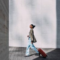 confident woman walking with red suitcase in modern urban setting - travel stock pictures, royalty-free photos & images