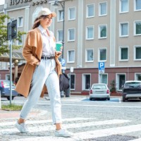confident young lady strolls along paved sidewalk in downtown taking sips from coffee cup - fashion stock pictures, royalty-free photos & images