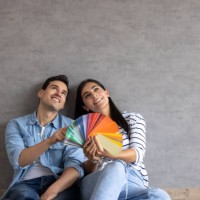 couple at home thinking about painting the walls and holding a color swatch - home decoration stock pictures, royalty-free photos & images