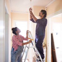 couple changing light bulb in corridor - home decoration stock pictures, royalty-free photos & images