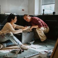 couple discussing over mobile phone while renovating kitchen at home - home decoration stock pictures, royalty-free photos & images