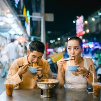 couple enjoying hot noodles at night street market - food stockfoto's en -beelden
