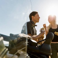 couple enjoying meal by motorcycle against sky on sunny day - junk food stock pictures, royalty-free photos & images