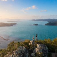 couple enjoying the view on top mountain overlooking whitsundays ocean - travel stock pictures, royalty-free photos & images