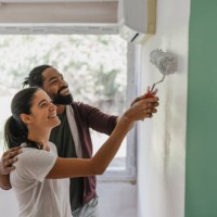 couple having fun painting a wall together - home decoration stock pictures, royalty-free photos & images