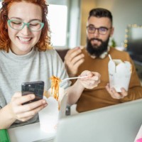 couple is taking a lunch break while working from home and eating fast food - junk food stock pictures, royalty-free photos & images