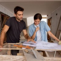 couple looking at the blueprint of their new house at the construction site - home decoration stockfoto's en -beelden