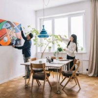 couple looking for perfect place to hang their painting - home decoration stock pictures, royalty-free photos & images