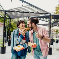 couple on the street eating fast food - junk food stock pictures, royalty-free photos & images