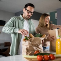 couple returning home from shopping trip and unpacking grocery bags - food stock pictures, royalty-free photos & images