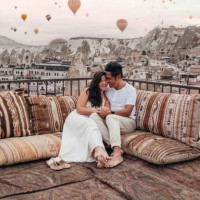 couple romantique en cappadoce assis sur un toit et regardant les montgolfières dans le ciel - travel photos et images de collection