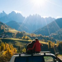 couple sit on car rooftop looking at mountains in the distance - travel stock-fotos und bilder