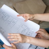 couple sits on the floor of an unfinished room and reviewing blueprints - home decoration stock pictures, royalty-free photos & images