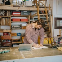 craftsman writing in book while taking order through phone in antique shop - home decoration stockfoto's en -beelden